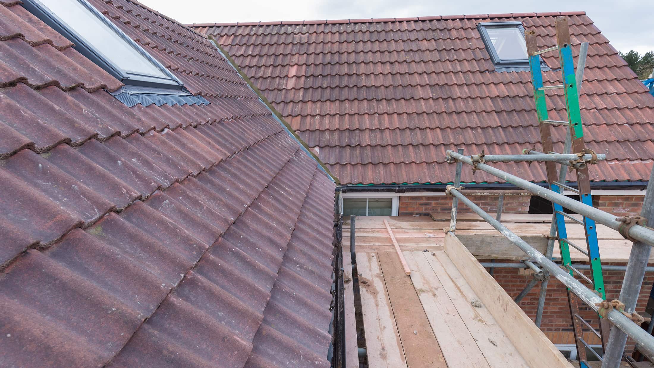 A house part way through a re-roof, with new tiles, roof windows and scaffolding
